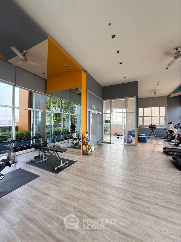 Spacious modern gym with large windows and exercise equipment in a residential building.