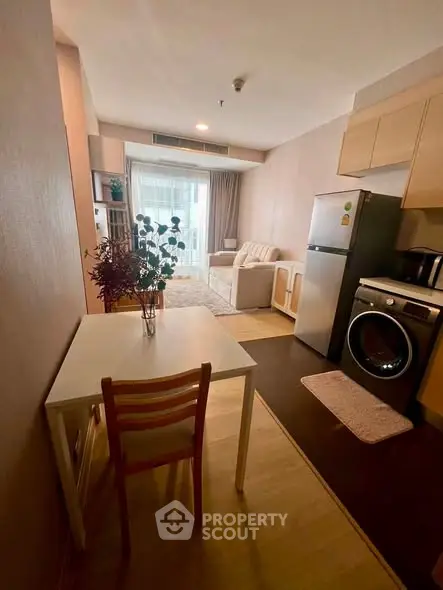 Cozy studio apartment with modern kitchen and living area, featuring a washing machine and fridge.