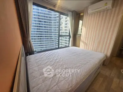 Modern bedroom with large window offering stunning city view in high-rise apartment.