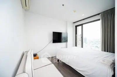 Modern bedroom with city view, featuring a wall-mounted TV and sleek furnishings.