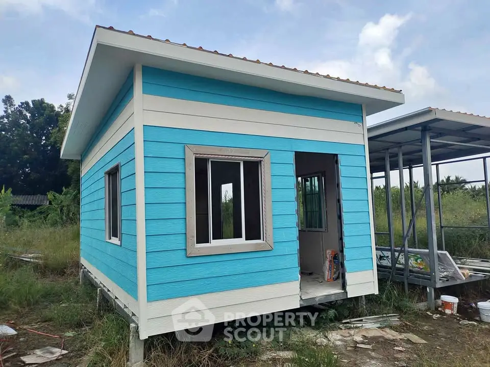 Charming small blue house with white trim in a serene natural setting, perfect for a cozy retreat.
