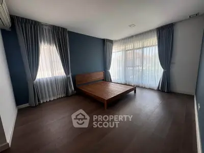 Spacious bedroom with large windows and wooden flooring, perfect for natural light lovers.