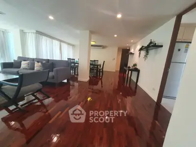 Spacious open-plan living and dining area with polished wooden floors and modern furnishings.