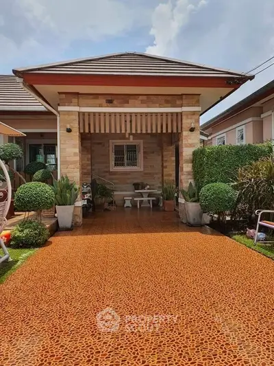 Charming single-story house with unique patterned driveway and lush greenery.