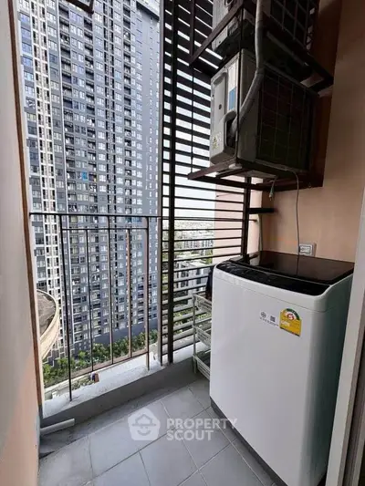 Compact balcony with washing machine and city view in modern high-rise apartment.