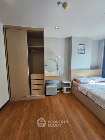 Spacious bedroom with wooden flooring, built-in wardrobe, and cozy bed setup.
