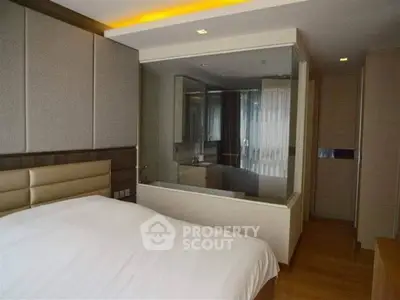 Modern bedroom with glass wall overlooking luxurious bathroom