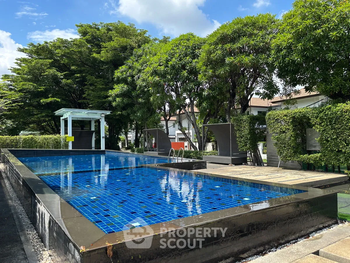 Luxurious outdoor pool area with lush greenery and modern lounge chairs, perfect for relaxation.