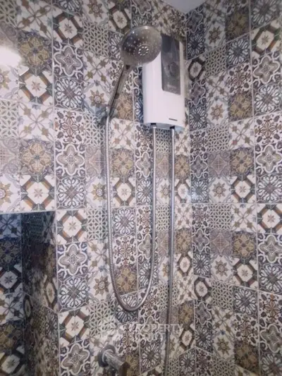 Stylish bathroom with intricate patterned tiles and modern shower fixture.