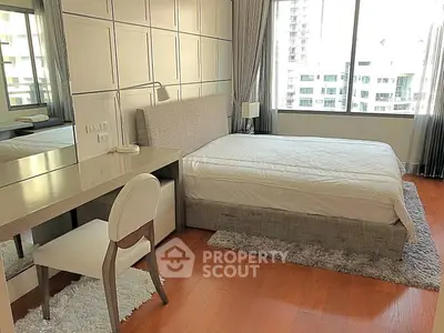 Spacious bedroom with modern decor and large window offering city views.