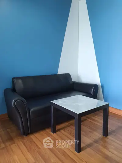 Modern living room with stylish black sofa and sleek coffee table against blue accent wall.