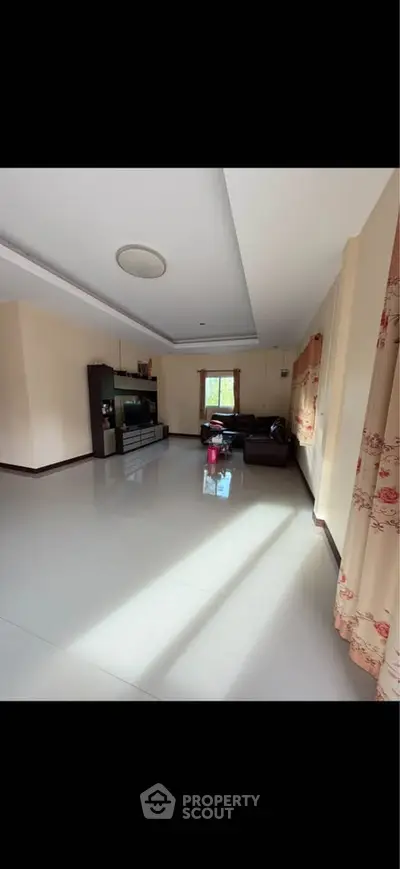 Spacious living room with modern decor and ample natural light, perfect for family gatherings.
