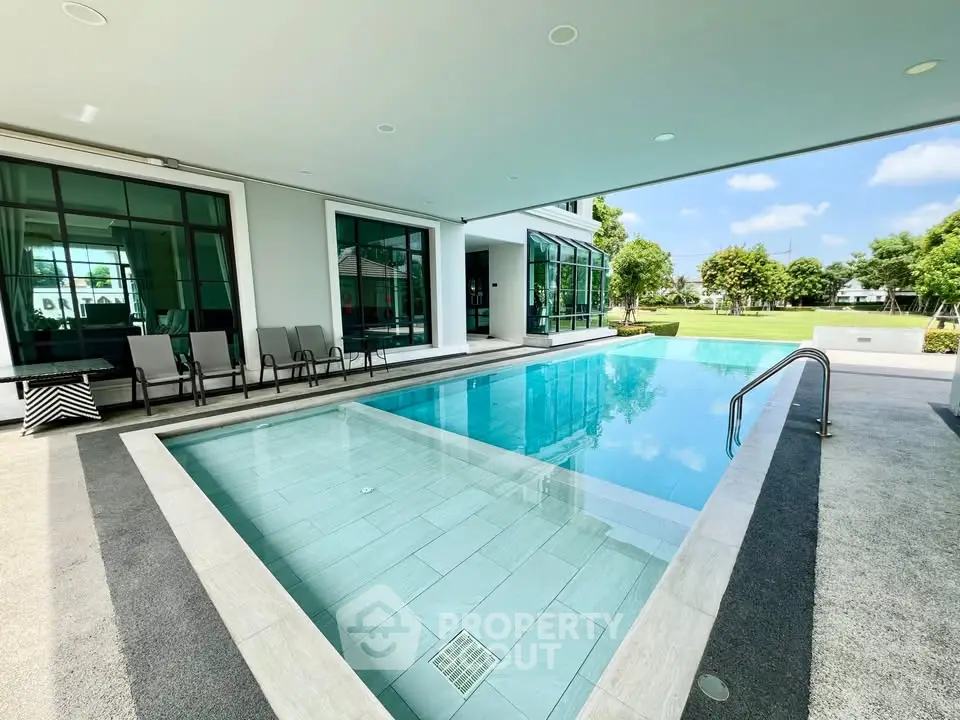 Luxurious modern home with stunning pool and lush garden view, perfect for relaxation and entertainment.