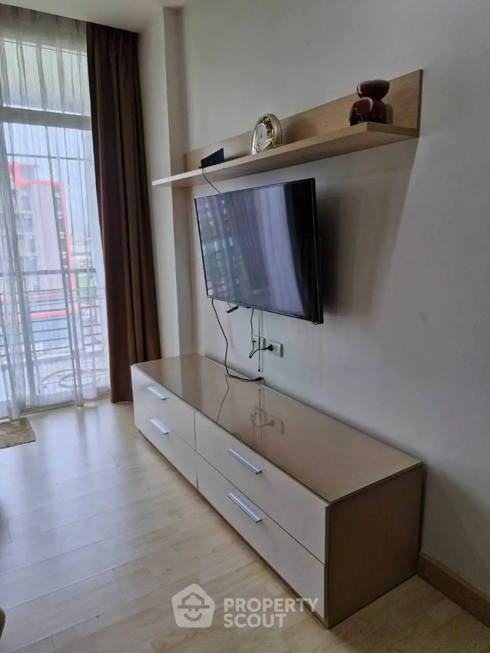 Modern living room with wall-mounted TV and sleek storage unit, featuring floor-to-ceiling windows for natural light.
