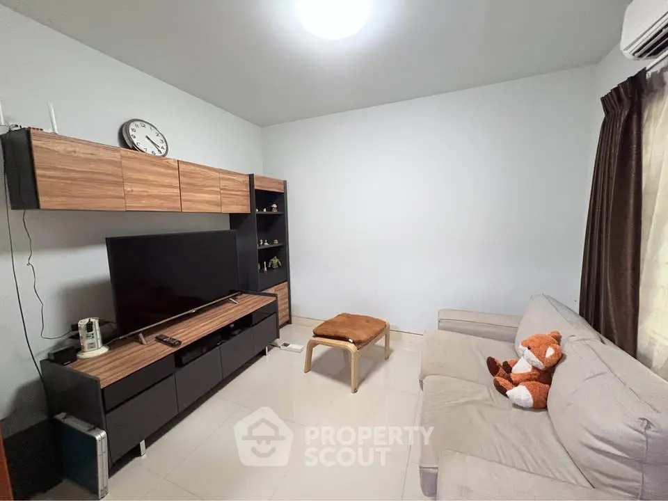 Cozy living room with modern furniture and wall-mounted TV, perfect for relaxation.