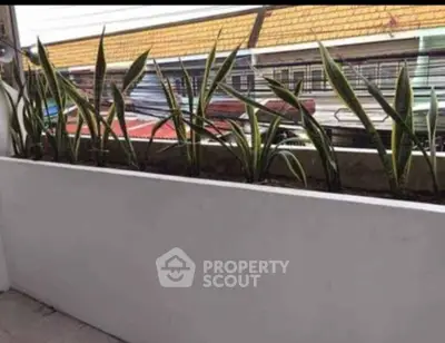 Modern balcony with sleek planter and lush greenery, offering a serene urban view.