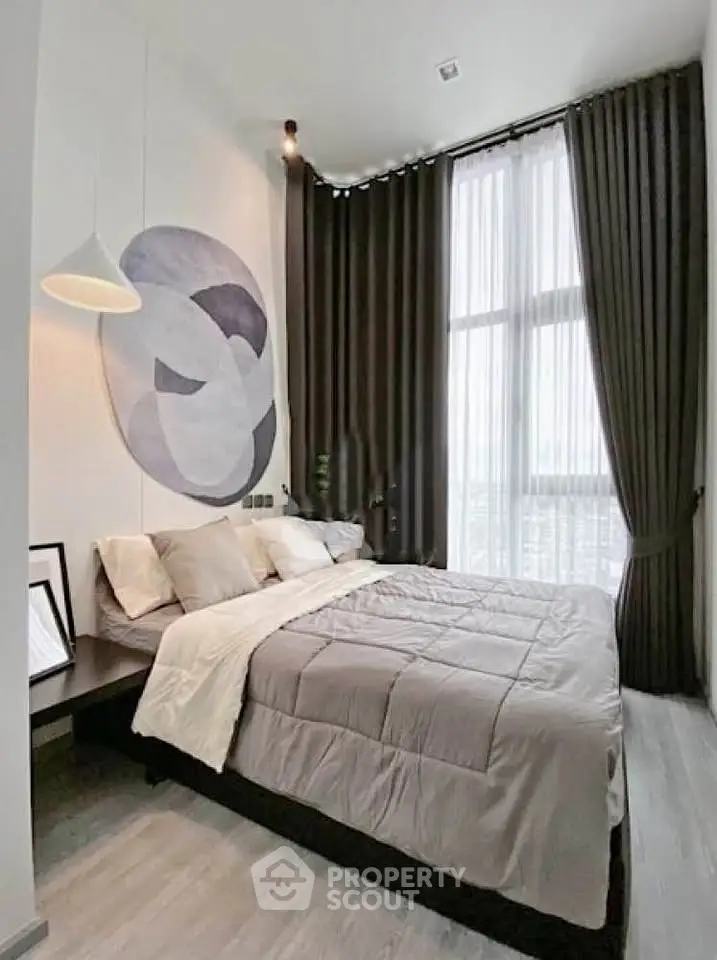 Modern bedroom with high ceilings and large windows, featuring elegant decor and cozy bedding.