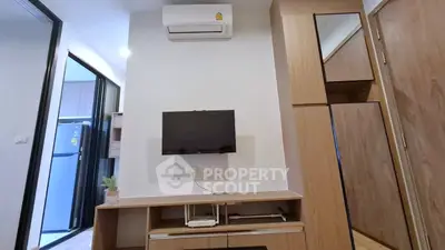 Modern apartment interior with air conditioning and sleek wooden furniture, featuring a compact TV setup.