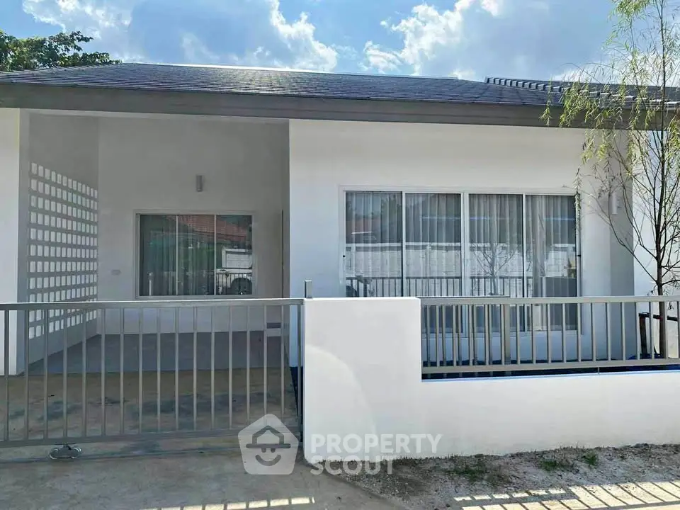 Modern single-story house with large windows and a gated front yard.