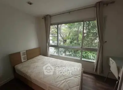 Cozy bedroom with large window offering lush green views, perfect for nature lovers.