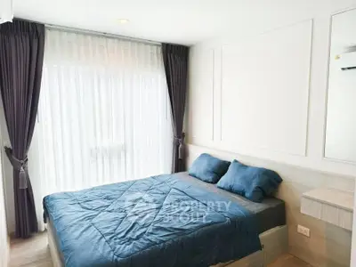 Modern bedroom with blue bedding and large window with curtains