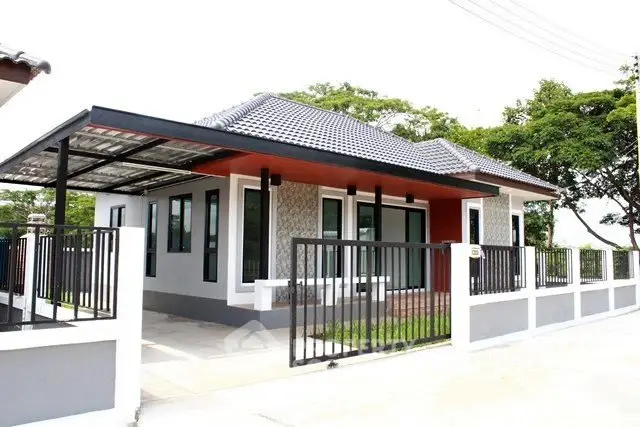 Modern single-story house with gated driveway and tiled roof in a serene neighborhood.