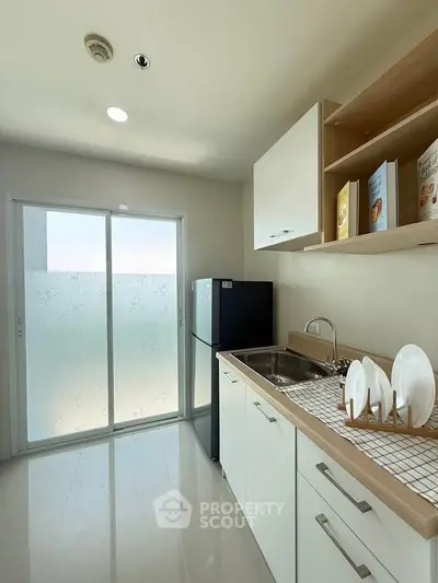 Modern kitchen with sleek cabinets and large fridge in bright apartment