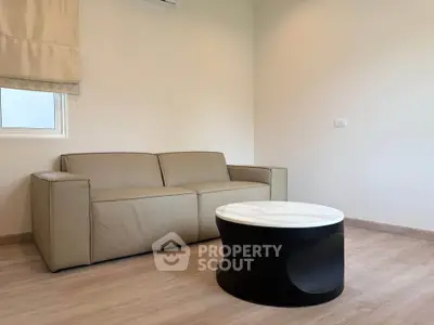 Modern living room with beige sofa and stylish round coffee table on wooden floor.