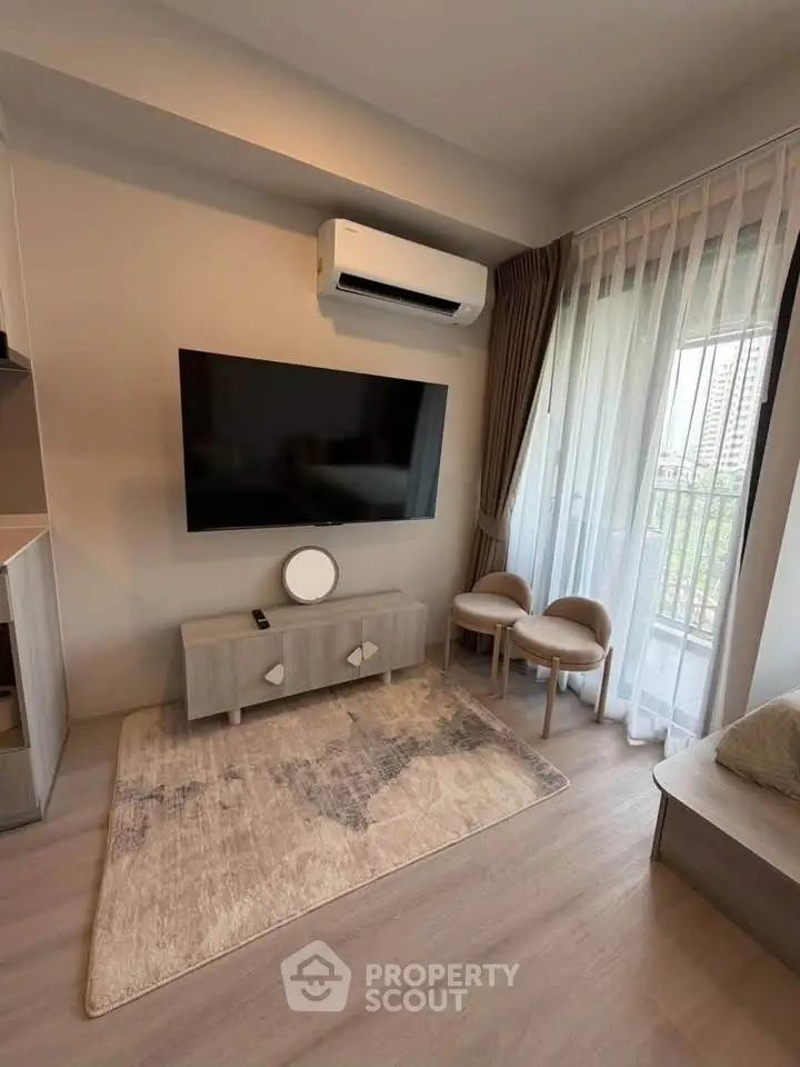 Modern living room with large TV, air conditioning, and balcony view in stylish apartment.