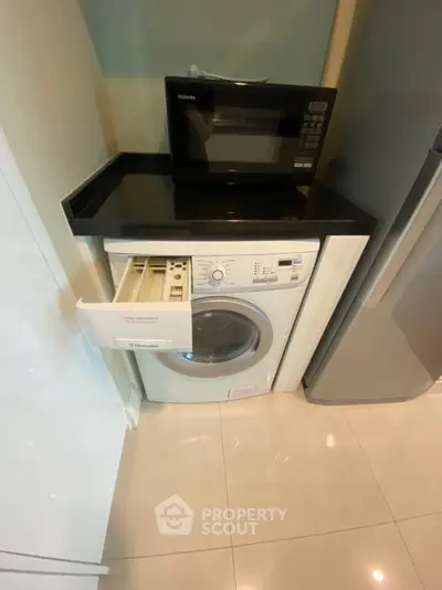 Modern kitchen with washing machine and microwave in compact layout