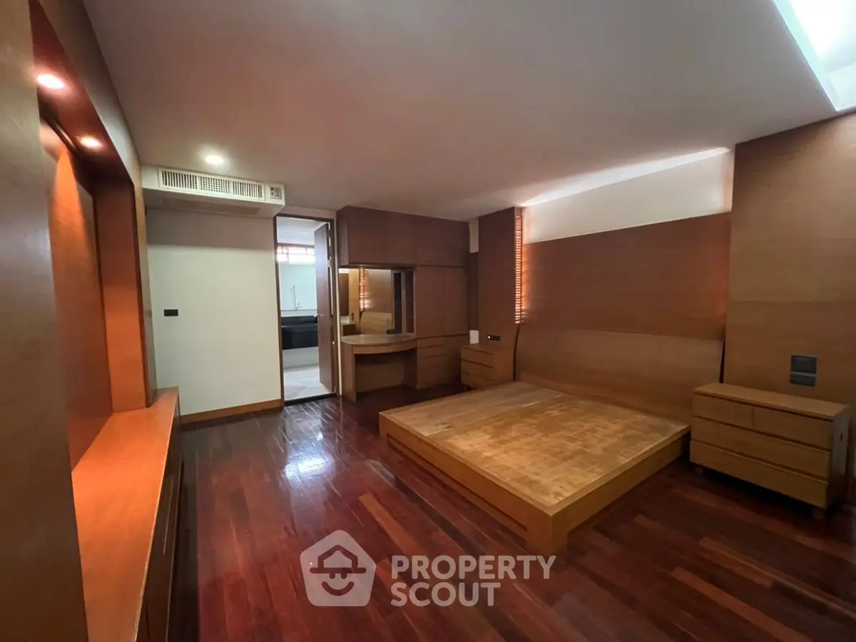 Spacious modern bedroom with wooden flooring and built-in furniture