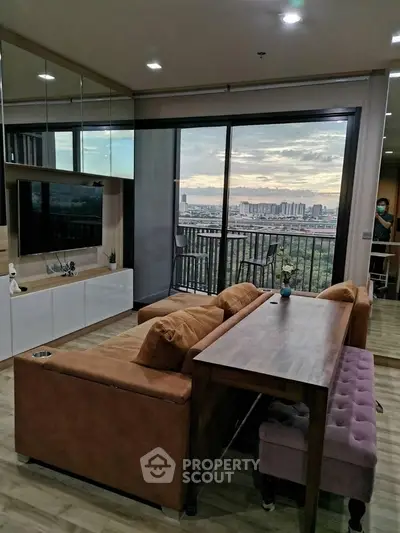 Modern living room with large windows offering stunning city views and stylish furniture.