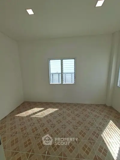 Spacious empty room with tiled floor and natural light through windows