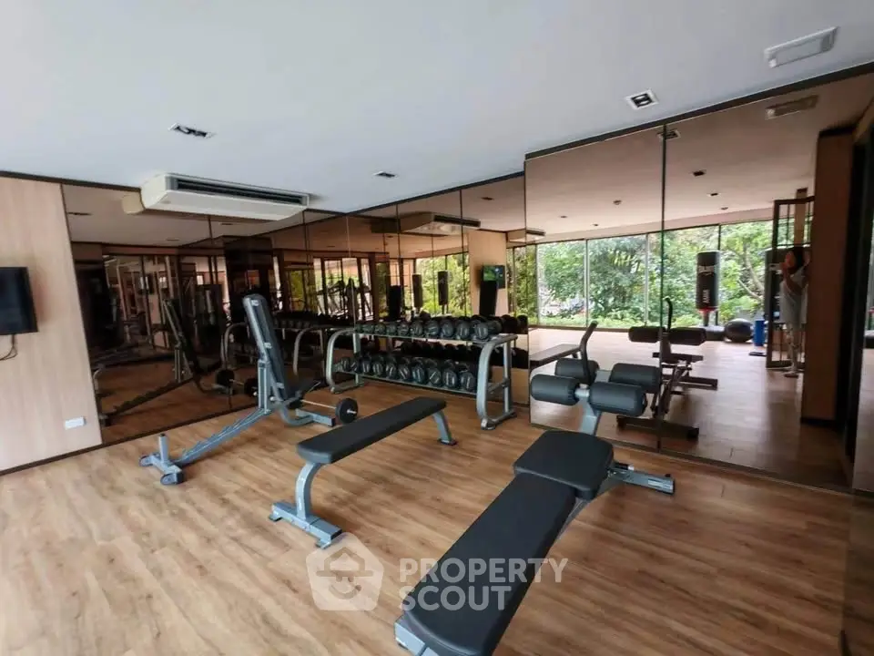 Modern gym with mirrored walls and fitness equipment in a residential complex.