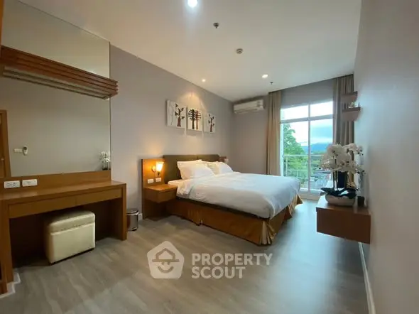 Spacious bedroom with modern decor and large window offering scenic views.
