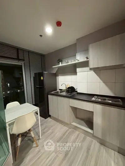 Modern kitchen with sleek cabinetry and dining area in stylish apartment.