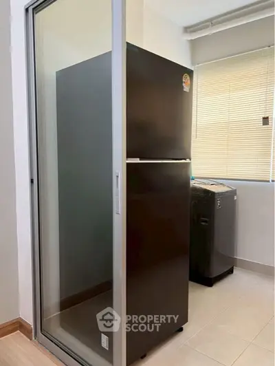 Modern kitchen with sleek black fridge and washing machine in a bright utility area.