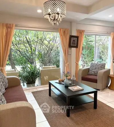 Charming living room with elegant chandelier and garden view, perfect for relaxation and entertaining.