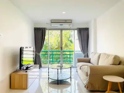 Bright and airy living room with modern furnishings and large windows overlooking greenery.