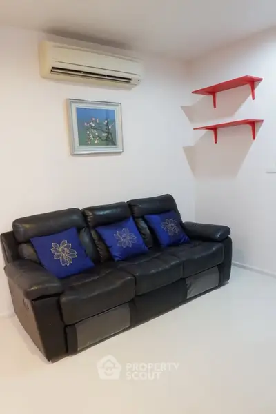 Cozy living room with black leather sofa and air conditioning