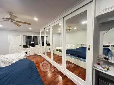 Spacious bedroom with mirrored closets and wooden flooring