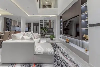 Luxurious modern living room with elegant decor and open layout, featuring a large TV and stylish furniture.