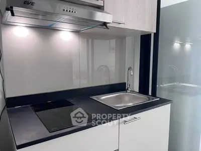 Modern kitchen with sleek design featuring induction cooktop and stainless steel sink.