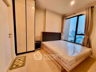 Modern bedroom with city view, featuring a sleek wardrobe and large window for natural light.