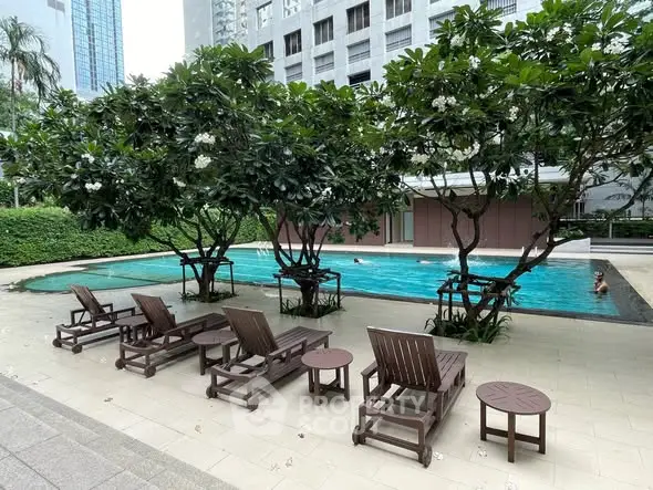 Luxurious outdoor pool area with lush greenery and comfortable lounge chairs in a modern residential complex.