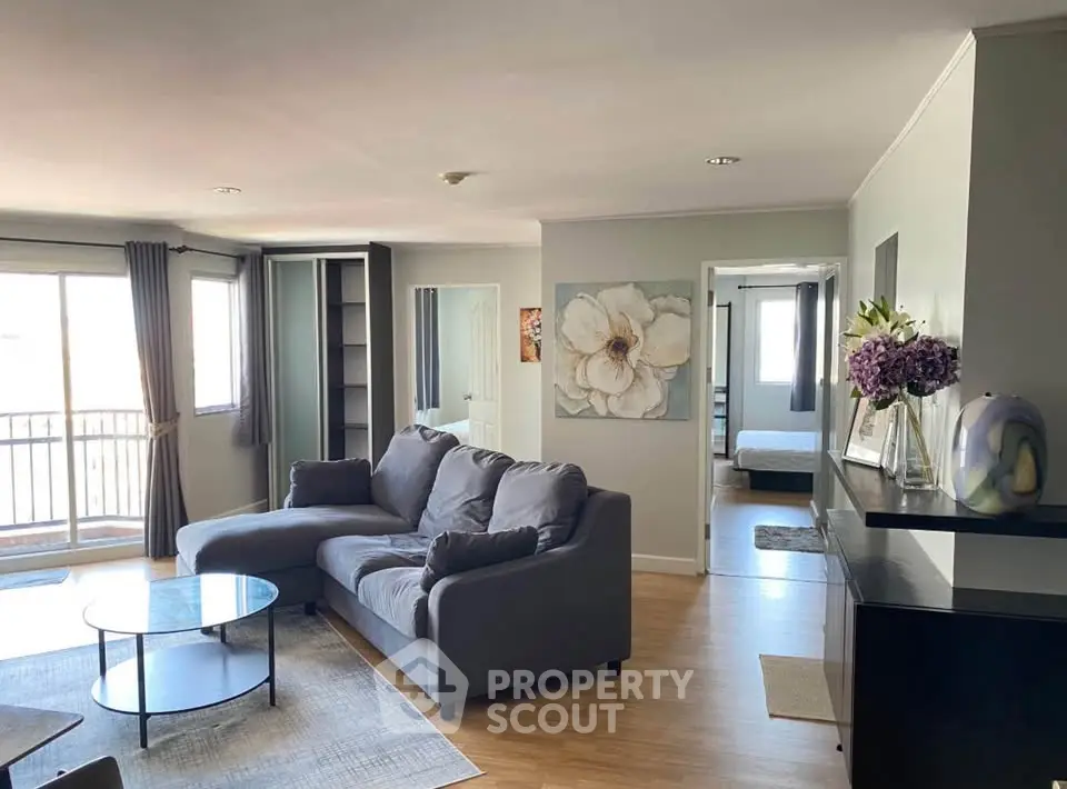 Spacious living room with modern decor and natural light, featuring a cozy sofa and elegant artwork.