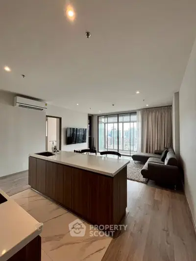 Spacious modern living room with open kitchen and city view balcony.