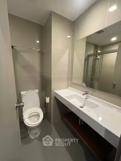 Modern bathroom with sleek fixtures and large mirror in contemporary apartment.