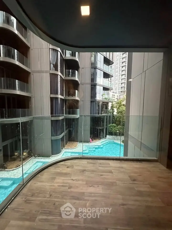 Modern apartment with floor-to-ceiling windows overlooking a luxurious pool and cityscape.