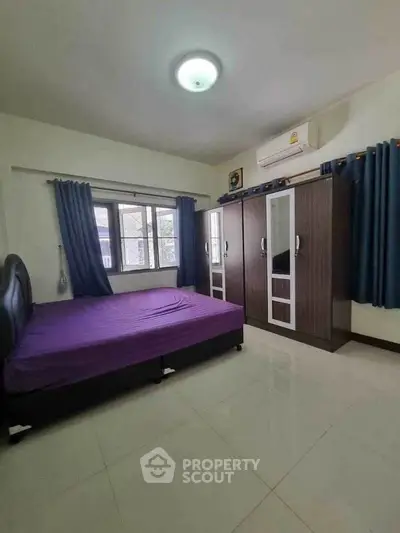 Spacious bedroom with modern wardrobe and large window for natural light.